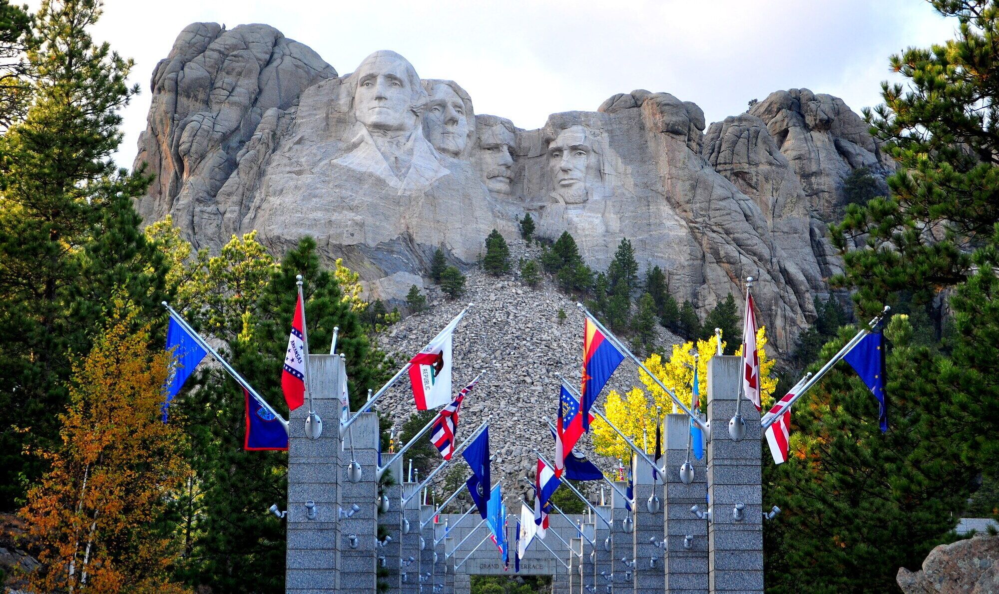 Un monument aux multiples facettes, entouré de drapeaux et d’une structure en pierre.
