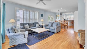 A spacious living room with a large sofa, a coffee table, and a dining area with wooden chairs. - Award-Winning Resort Amenities | Grand Pavilion 21 (Isle of Palms)