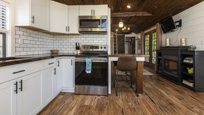 A kitchen with white cabinets, a stainless steel oven, and a wooden ceiling. - Modern Pond-View Cabin Near Lake of Egypt (Marion)