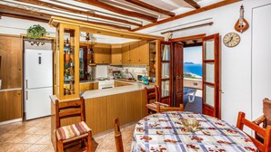 Une cuisine compacte avec des meubles en bois, un four encastré et une vue sur la mer par une porte ouverte.