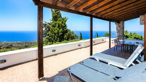 Un espace extérieur abrité, doté de chaises longues et offrant une vue sur la mer.