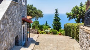 Un bâtiment en pierre avec un chemin de gravier menant à un point de vue pittoresque sur la mer.
