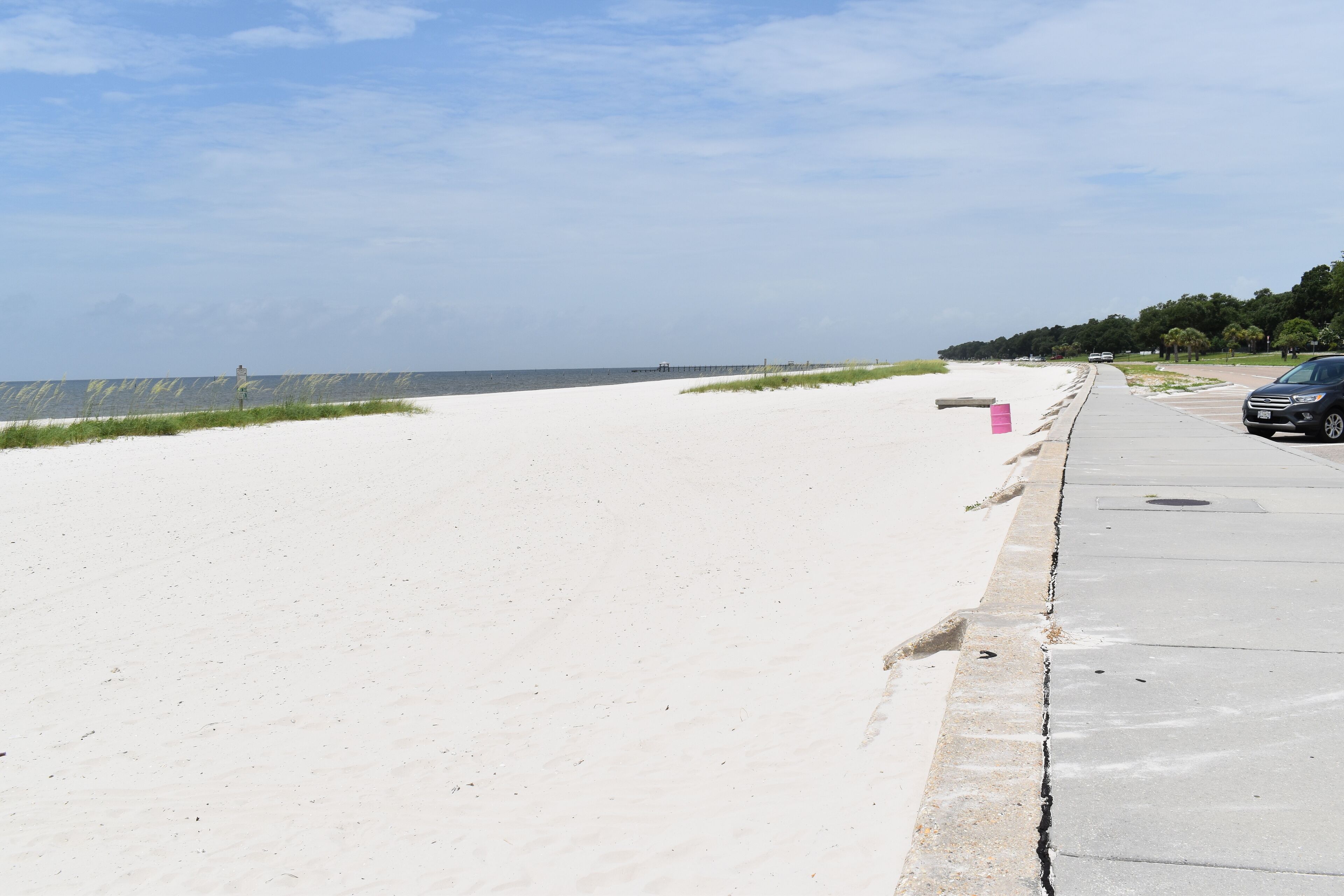 Une plage avec une promenade en béton et une voiture garée.