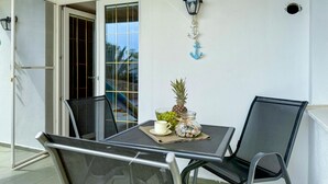 A patio with a table, chairs, a lantern, and a decorative wall piece.