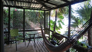 A covered outdoor area with a hammock, a table, and chairs. - Water Front Casita w pool On Tropical One Acre Estate (Roatan)