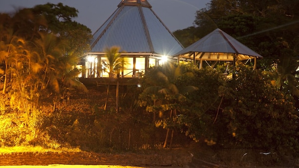 A building with a triangular roof, surrounded by vegetation. - Water Front Casita w pool On Tropical One Acre Estate (Roatan)