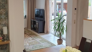 A living room with a television, a potted plant, and a sliding glass door leading to a balcony. - Elisa Apartment Noswendel am See (Noswendel am See)