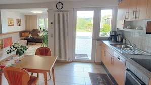 A modern kitchen with a dining area, a radiator, a clock, and a view of the outdoors. - Elisa Apartment Noswendel am See (Noswendel am See)