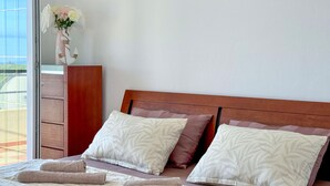 A neatly made bed with two pillows, a wooden headboard, and a vase with flowers on a nightstand. - Beautiful apartment in Labin with WiFi (Labin)