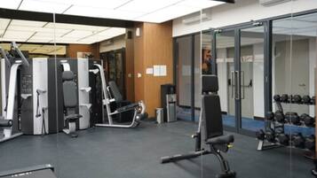 A gym with various exercise machines, a bench, and a rack of dumbbells.