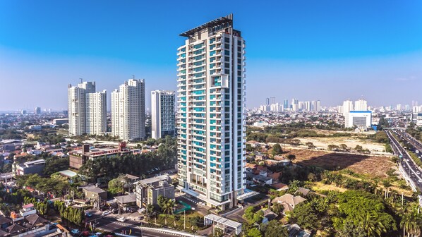 A high-rise building with multiple balconies, surrounded by other residential buildings and a highway. - Veranda Serviced Residence Puri (Jakarta)