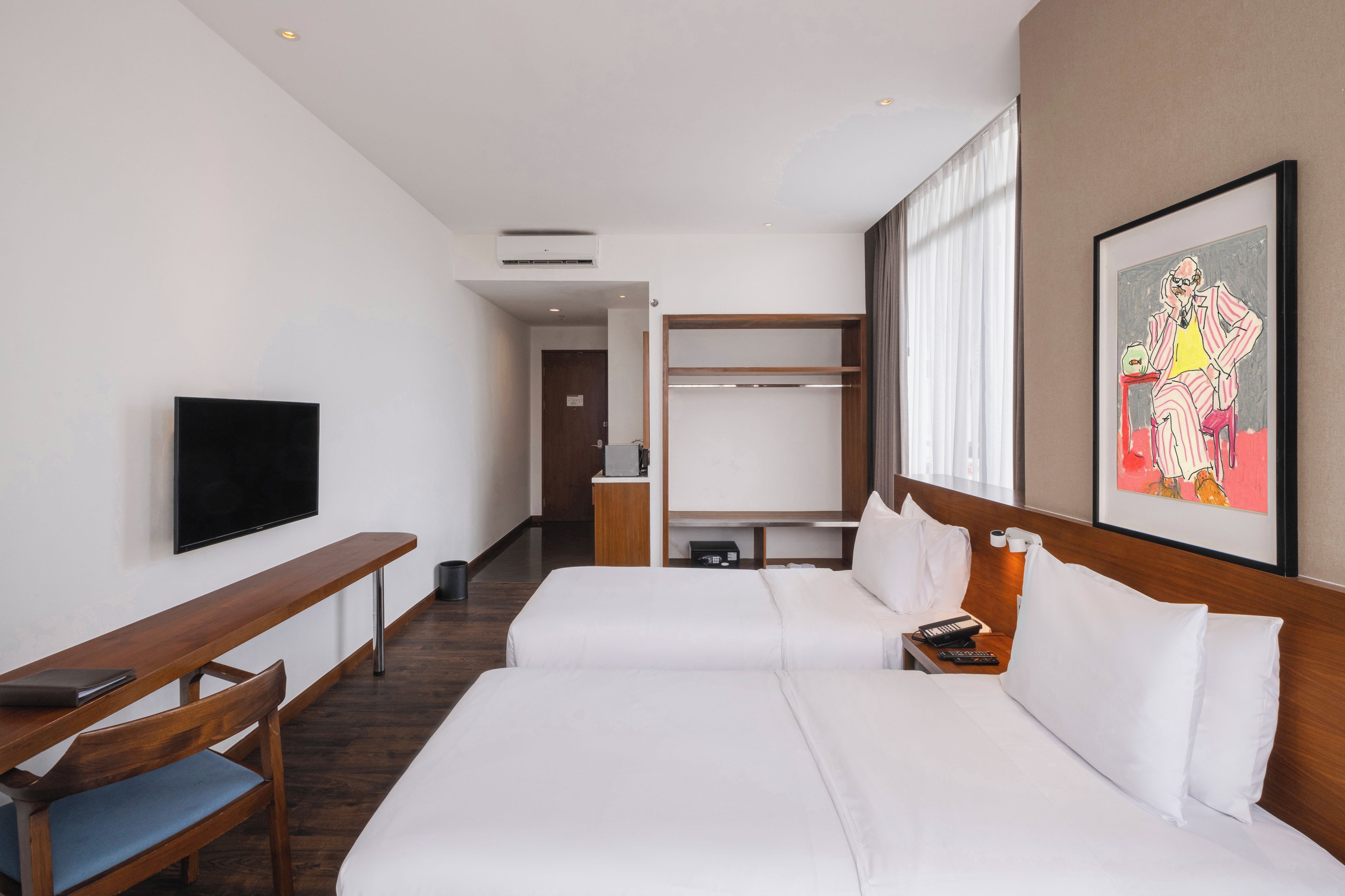A hotel room with a bed, a TV, a desk, and a wardrobe.