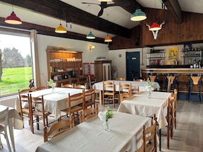 A restaurant with wooden interiors, multiple tables, and hanging pendant lights. - Studio in the old hayloft (Chalais)