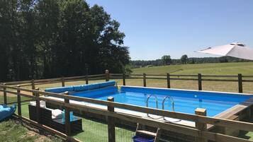 Una piscina rectangular con un muelle de madera y una valla.
