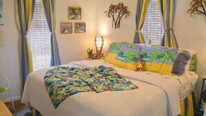 Una camera da letto con un letto, tende, un comodino, una lampada e decorazioni alle pareti.