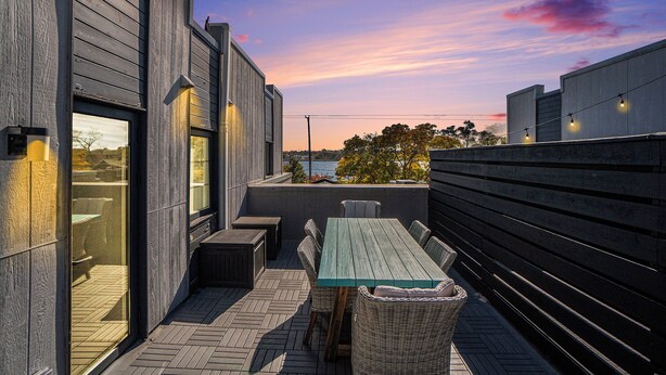 Eine Terrasse im Freien mit einem Holztisch und -stühlen, Blick zum Himmel und einem Holzzaun.