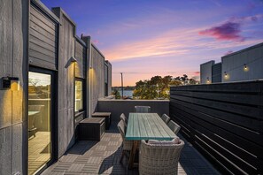 An outdoor patio with a wooden table and chairs, a view of the sky, and a wooden fence. - Modern Lake View Condo Located Downtown Saugatuck with Spacious Rooftop Patio (Saugatuck)