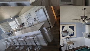 Una cocina moderna con armarios blancos, una isla central con taburetes y electrodomésticos como microondas y estufa, además de un ventilador de techo.