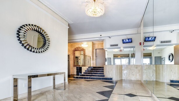 Een moderne lobby met een marmeren vloer, een ronde spiegel en een trap naar een ander gedeelte.