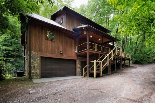 Une cabane rustique avec des fondations en pierre, un revêtement extérieur en bois et un escalier en bois menant à une véranda.