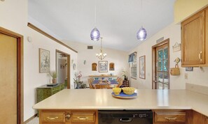 Una cocina con una isla central, armarios de madera y luces colgantes.
