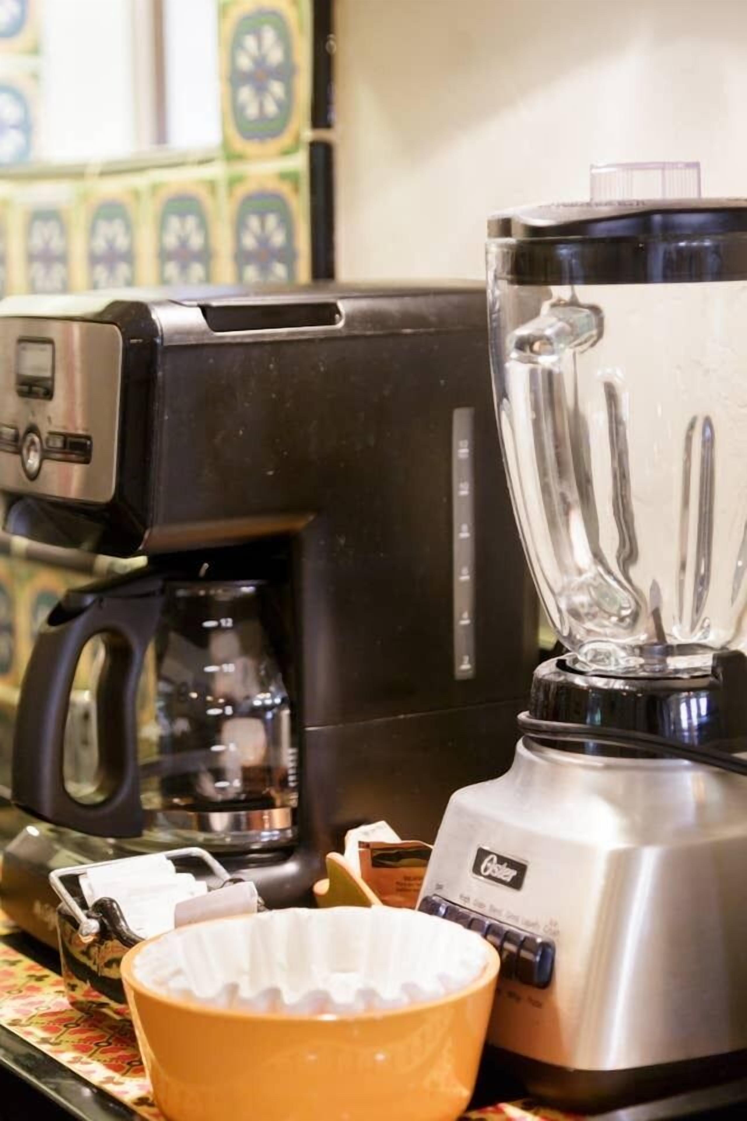 Een keuken met een koffiezetapparaat en een blender op het aanrecht.