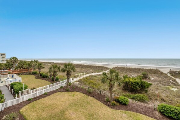 A beachfront property with a white fence, palm trees, and a clear view of the ocean. - 2nd Floor Beach Club III. Oceanfront Pools, Sundecks | Beach Club III - 2E (North Myrtle Beach)