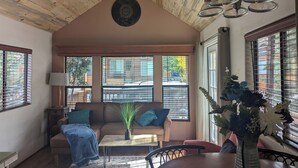 A cozy living room with a wooden ceiling, a sofa, a coffee table, and a vase of flowers.