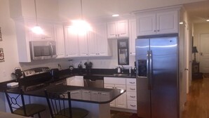 Una cocina moderna con armarios blancos, electrodomésticos de acero inoxidable y una isla central con taburetes de bar.