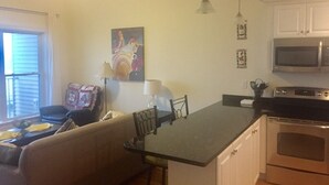 Una cocina compacta con comedor, microondas, horno y un cuadro en la pared.