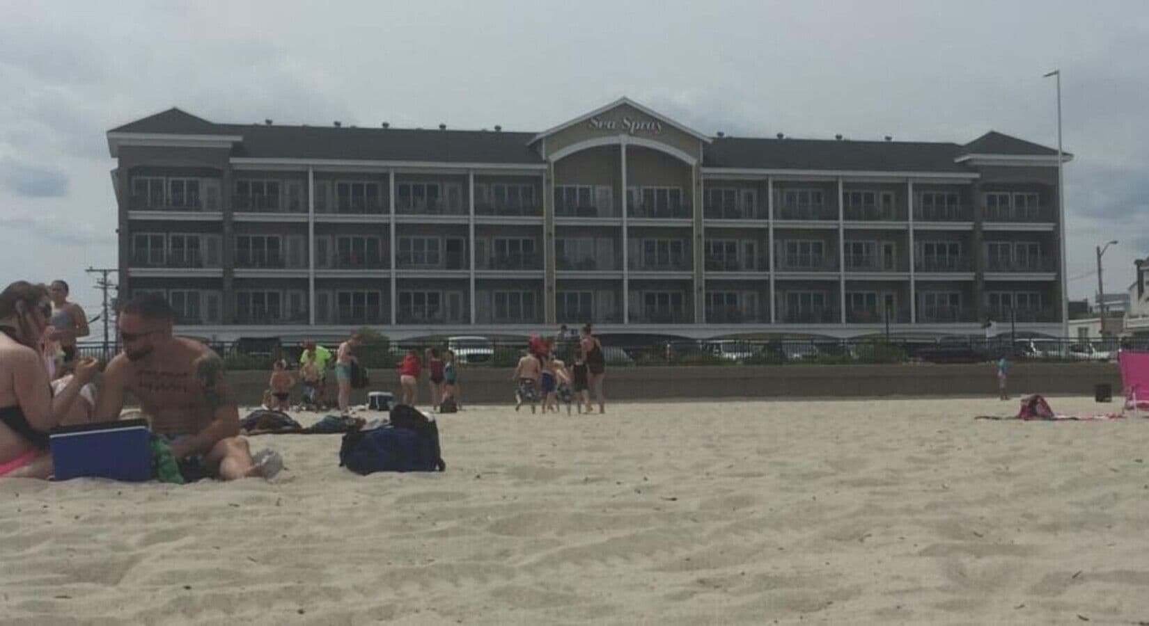 Een hotel met een groot gebouw, meerdere balkons en een zandstrand ervoor.