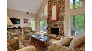 A spacious living room with a stone fireplace, large windows, and comfortable seating.