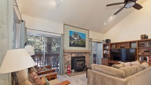 A living room with a stone fireplace, a television, and a bookshelf.