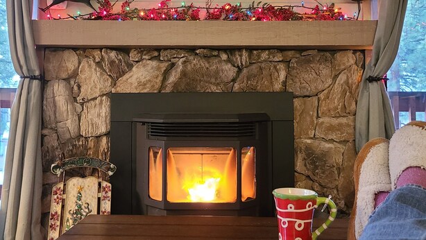 A fireplace with a stone surround, a painting of a mountain landscape above it, and a decorative bird on the mantel.