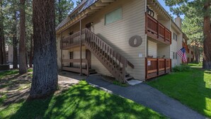 A two-story lodge with a wooden staircase, a balcony, and an American flag.