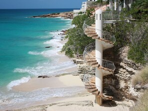 A spiral staircase leading down to a beach with turquoise waters. - Spectacular View Ocean Front w/New Furnishings On Private Beach! (Cupecoy)