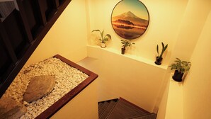 A staircase with a pebbled area, a wall-mounted painting of a mountain, and potted plants. - 心乃宿 Kokoro No Yado (Nagoya)