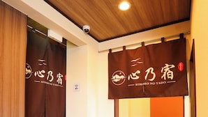 A hotel interior with a wooden ceiling, a reception desk, and a sign with Japanese characters. - 心乃宿 Kokoro No Yado (Nagoya)