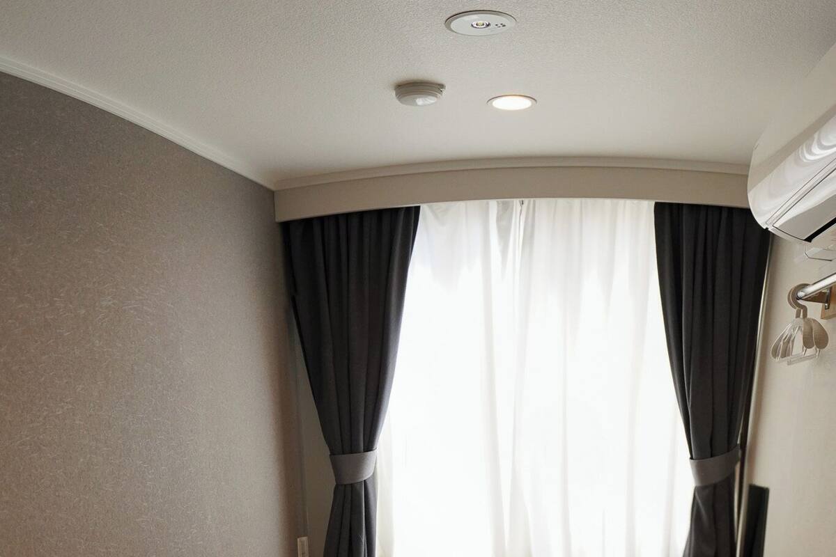 A hotel room with a single bed, a desk, and a window with curtains.