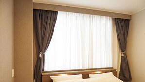 A hotel room with a large bed, a nightstand, and a window with curtains. - 心乃宿 Kokoro No Yado (Nagoya)