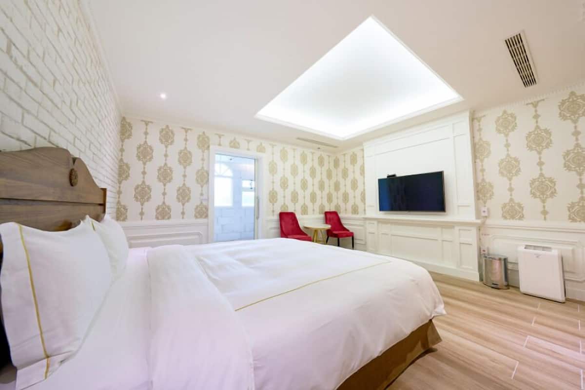 Ein Hotelzimmer mit einem großen Bett, einem Dachfenster, einem Fernseher und einem kleinen Tisch.