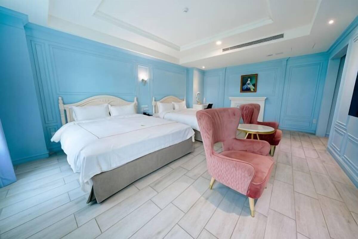 Ein Schlafzimmer mit einem großen Bett, einem rosa Sessel und einem kleinen runden Tisch.