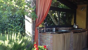 An outdoor kitchen area with a brick counter, a sink, and a kettle. - Podere La Piana (Fivizzano)