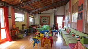 A spacious room with a wooden ceiling, a green sofa, a dining table with chairs, and a small kitchen area. - Podere La Piana (Fivizzano)