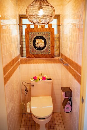 Un baño con inodoro, lavamanos con espejo decorativo y lámpara colgante.