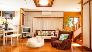 A modern living room with a sofa, a bean bag, a TV, and a staircase. - MK Garden (Okinawa)