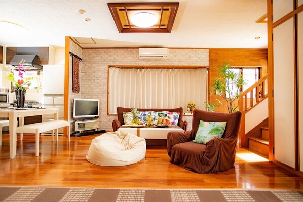 Una sala de estar moderna con un sofá, un sillón tipo puff, un televisor y una escalera.