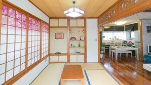 A traditional Japanese room with tatami flooring, a wooden table, and a sliding door with floral patterns. - MK Garden (Okinawa)