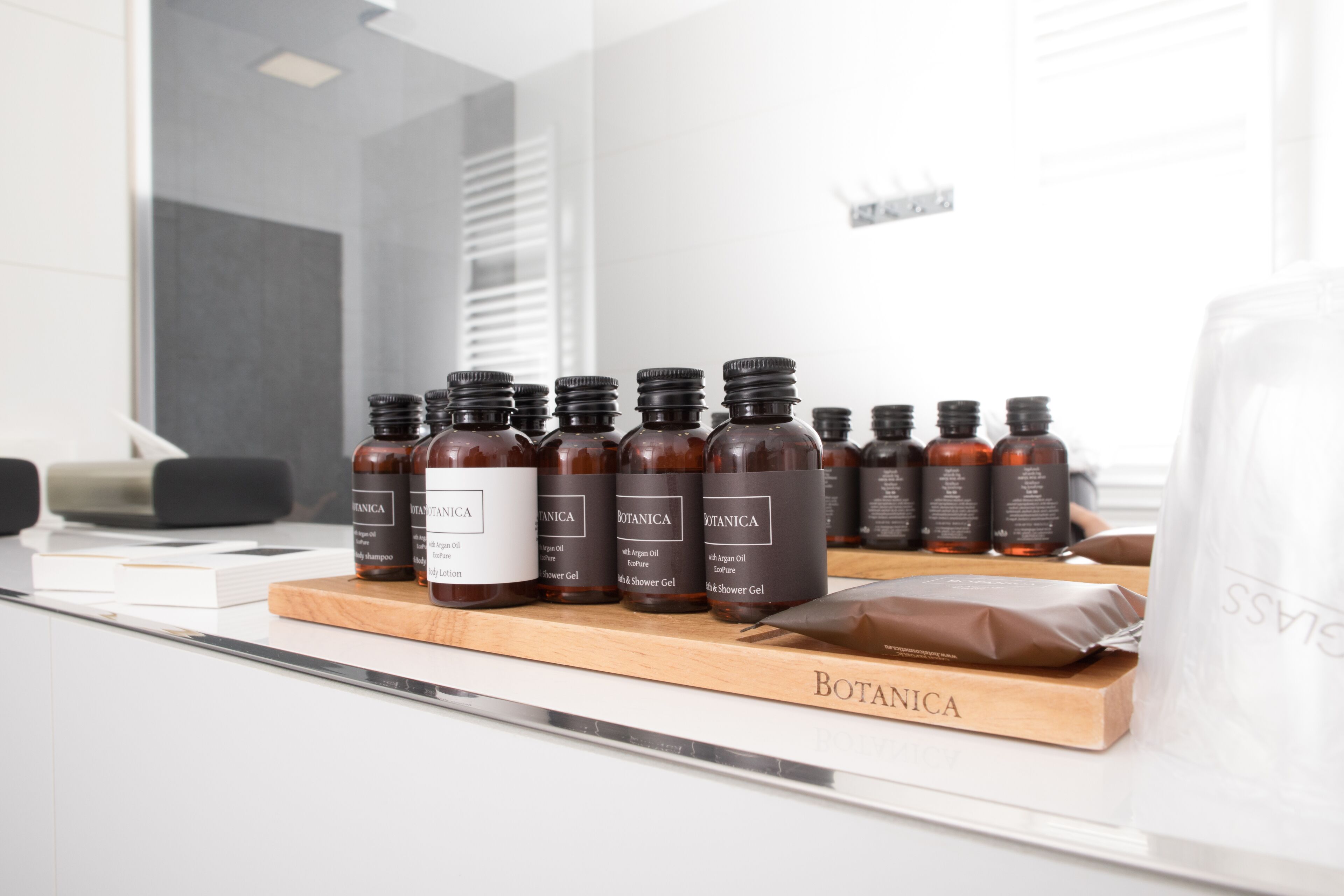 Une sélection de produits Botanica présentée sur un plateau en bois dans une salle de bain moderne.