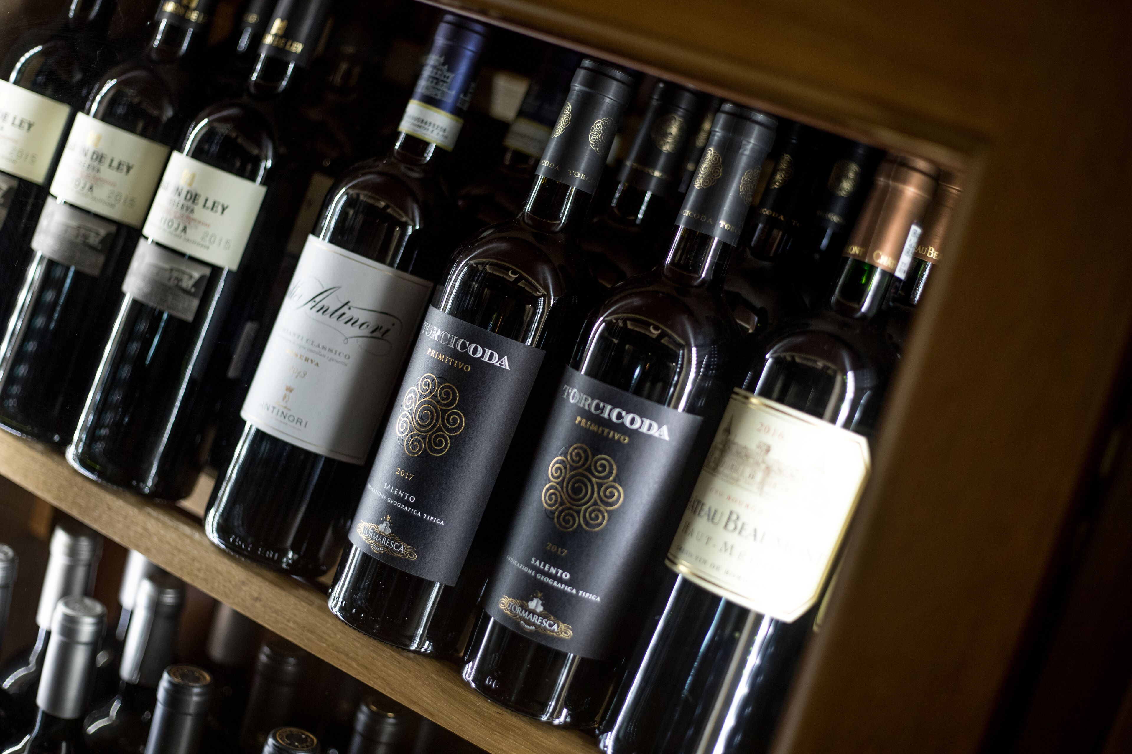 A wine rack with several bottles of wine, including Torriccoda and other brands.